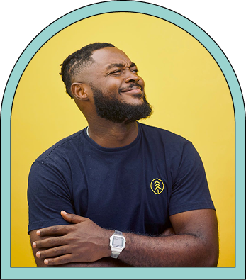 Smiling man with a beard wearing a navy blue t-shirt and silver watch, posing against a yellow background within a rounded frame.